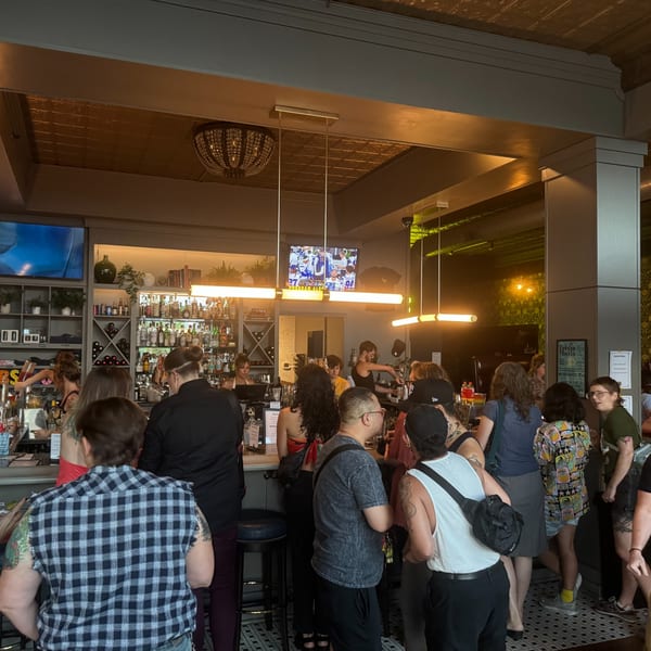 A lively bar scene at Luna & The Bear with patrons standing and bartenders serving drinks.