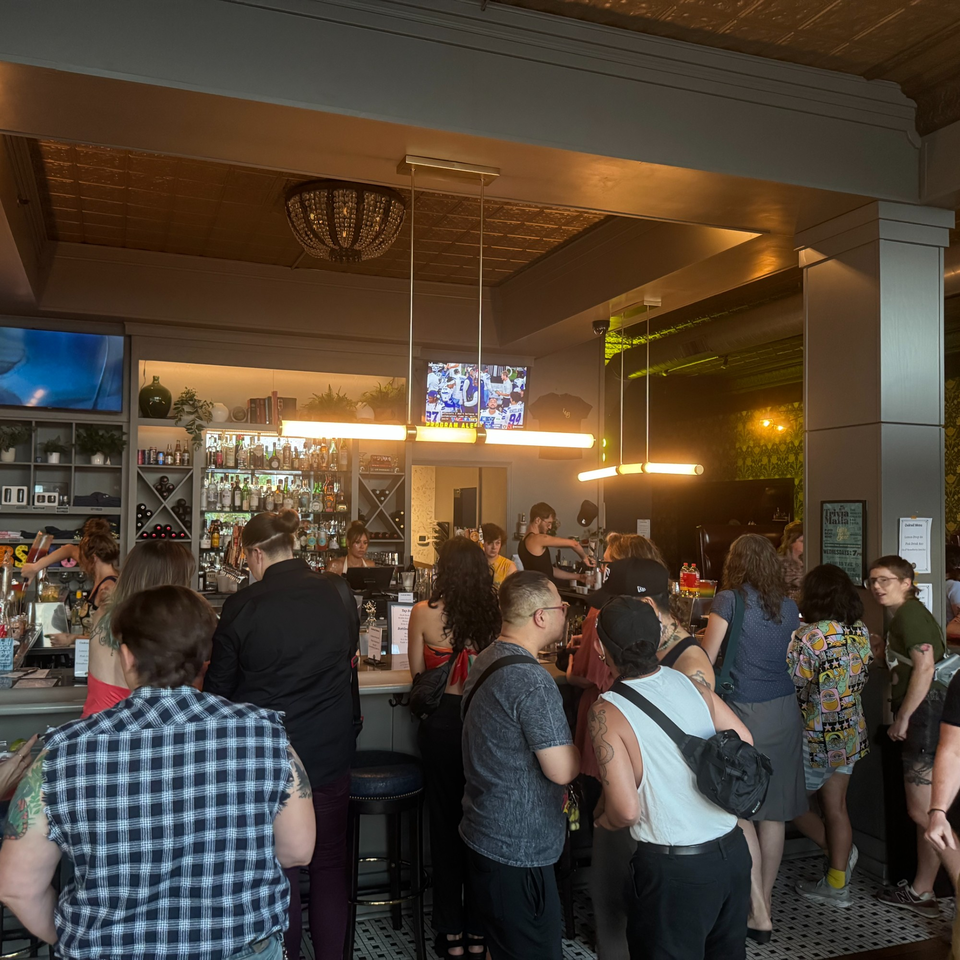A lively bar scene at Luna & The Bear with patrons standing and bartenders serving drinks.